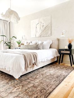 a bedroom with a bed, rug and painting on the wall above it's headboard