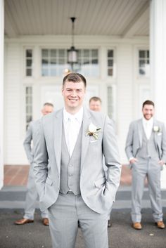 a group of men standing next to each other in front of a white building and wearing suits