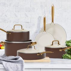 an assortment of pots and pans sitting on a counter top next to some vegetables