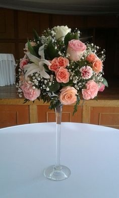 a vase filled with lots of pink and white flowers on top of a round table