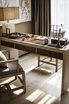 a wooden desk with two chairs and a lamp on it in front of a window