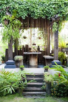 an outdoor dining area is surrounded by plants and greenery, with steps leading up to the table