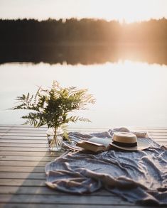 a hat, blanket and flowers on a wooden dock