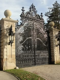 an iron gate with two lamps on each side