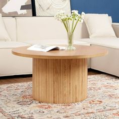 a vase with flowers sitting on top of a wooden table in front of a white couch