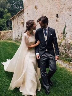 a bride and groom are walking in the grass near an old stone building with ivy growing on it