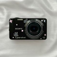 a black camera sitting on top of a white sheet with pink and blue stars all over it