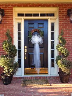 a front door decorated for christmas with wreaths and potted plants