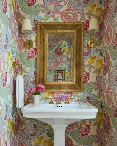 a white sink sitting under a mirror next to a wall mounted faucet in a bathroom