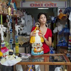 a woman standing in front of a table holding a figurine