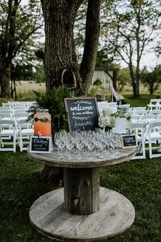 a wooden table topped with wine glasses next to a tree