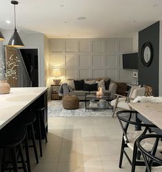 a living room filled with furniture next to a dining table and two lamps on top of it