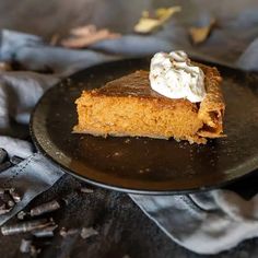 a piece of pumpkin pie with whipped cream on top is sitting on a black plate