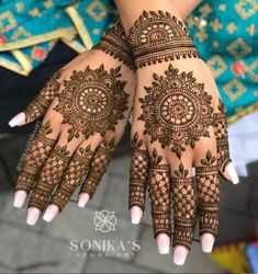 two hands with henna tattoos on them, one is showing off the intricate design