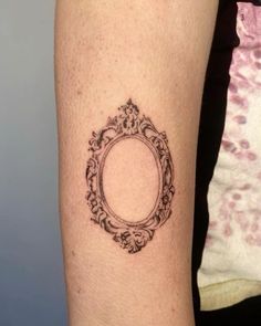 a woman's arm with a tattoo on it that has an oval frame in the middle