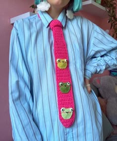 a woman with blue hair wearing a pink crocheted tie and matching frog brooch