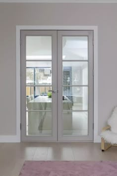 an empty room with two glass doors and a pink rug on the floor