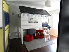 there is a bunk bed with a black roof and red bean bag chairs in the room