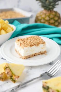 a piece of cake sitting on top of a white plate next to pineapples