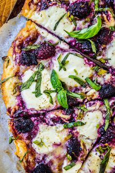 a pizza with cheese, blueberries and basil on it