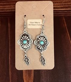 Silver look Floral Western wire earrings with tiny dangle with dream catcher. Perfect for the cowgirl in your life, young or old! Turquoise colored stone sits in middle of floral scalloped design. Custom made by Old Hands Creations. Made from zinc alloy and silver plate.  Please check out our other items as some are complimentary to this item. If you buy 2 or more items you will get 15% off, spend $50 and get 20% off. Pay only one shipping cost for multiple items. We take custom order requests a Western Jewelry Earrings, Scalloped Design, Feather Dream Catcher, Old Hands, Colored Stones, Earrings Turquoise, Colored Stone, Cow Girl, Western Jewelry