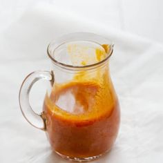 a glass pitcher filled with liquid sitting on top of a white cloth covered tablecloth