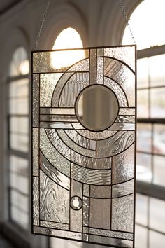 a stained glass sun catcher hanging from a window in front of a large arched window