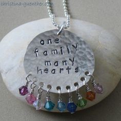 one family many hearts necklace with multi - colored swarongs on it sitting on top of a rock