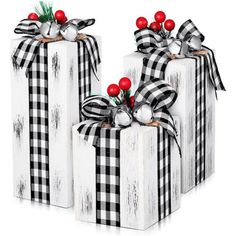 two black and white christmas gift boxes with red berries on the top one is wrapped in plaid fabric