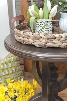 some flowers are sitting on top of a small table with a wicker basket around it