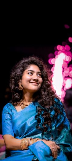 a smiling woman in blue sari sitting down