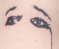 a woman's face with eyes drawn on her back shoulder and neck, in black ink