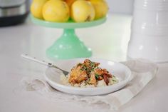 a white plate topped with food next to a bowl of lemons and other fruit