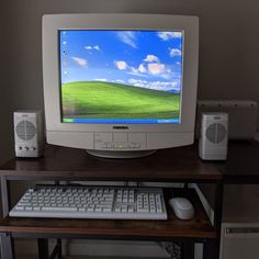 a computer monitor sitting on top of a wooden desk next to a keyboard and mouse