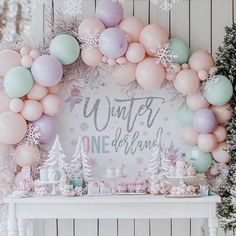 a table topped with balloons and snowflakes next to a sign that says winter is one