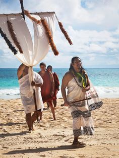 two men in native garb walking on the beach