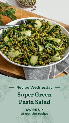 a white bowl filled with green pasta and cucumbers