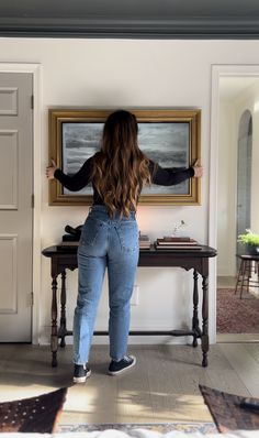 a woman standing in front of a painting on the wall