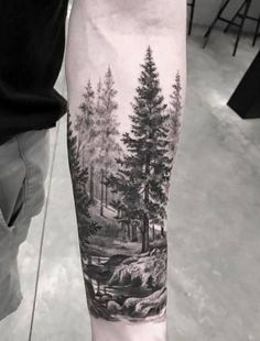 a man's arm with a forest scene on it