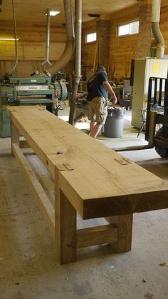 a man working on a wooden bench in a workshop