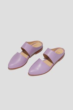 The mule is ZX’s perennial flat, inspired by traditional babouche slippers. With its sleek cut-out upper and almond shaped toe, this style makes feeling comfortable and pulled-together an easy task for days filled with lots of activity. This pair is crafted from vibrant lilac kidskin. Style yours with statement pants for a chic party look. Who it’s for: The woman with refined style who likes to go places by foot. Kidskin leather upper and undyed vegetable-tanned leather lining. Leather sole and stacked heel. Handmade in Argentina. Spring Leather Sole Slip-on Flats, Spring Slip-on Pointed Toe Clogs, Slip-on Pointed Toe Clogs For Spring, Modern Summer Slip-ons With Leather Sole, Spring Closed Toe Slides With Leather Sole, Modern Closed Toe Slip-on Slides, Chic Flat Slippers With Rubber Sole, Spring Flat Heel Clogs With Stitched Sole, Leather Slip-on Mules For Spring