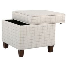 a white ottoman sitting on top of a wooden table next to a black drawer under it