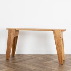 a wooden bench sitting on top of a hard wood floor next to a white wall