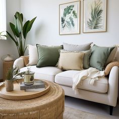 a living room with white couches and green pillows on top of the sofas