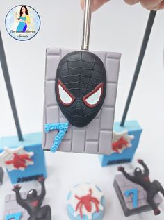 a spiderman cake is being held by someone's hand