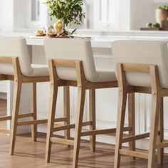 three white bar stools sitting in front of a counter top with flowers on it