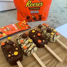 chocolate covered candy pops are on a cutting board next to a bag of reese's minis