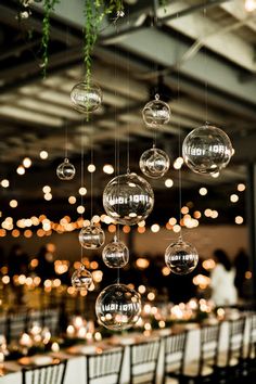 an arrangement of clear glass balls hanging from the ceiling in a banquet hall with white tables and chairs