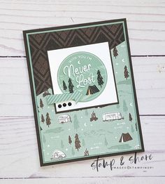 a close up of a card with a camper and tent on the front, next to a wood background