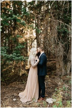 a man and woman standing next to each other in the woods